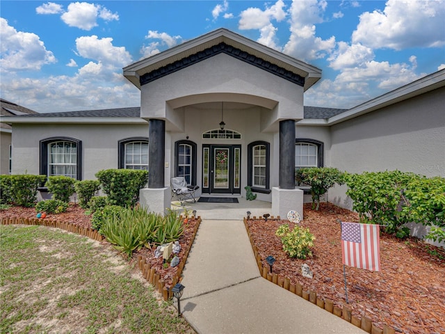 2033 Normandy Heights Dr, Winter Haven, FL 33880 - doorway to property with stucco siding, roof with shingles, and covered porch