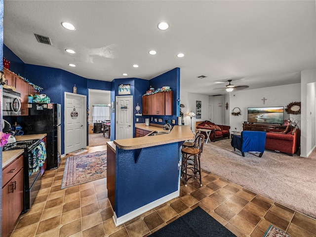 2033 Normandy Heights Dr, Winter Haven, FL 33880 - kitchen with black gas range oven, stainless steel microwave, a sink, recessed lighting, and a kitchen bar