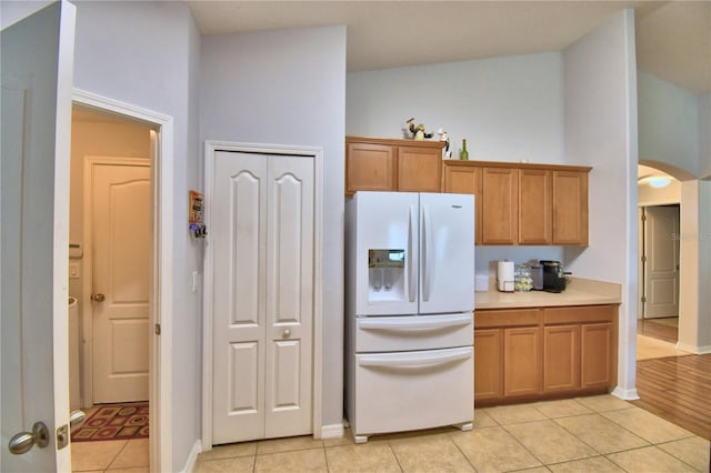 3684 Madbury Cir, Lakeland, FL 33810 - kitchen with light tile patterned flooring, baseboards, brown cabinetry, light countertops, and white fridge with ice dispenser