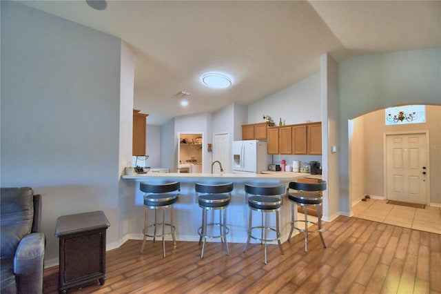 3684 Madbury Cir, Lakeland, FL 33810 - kitchen with white fridge with ice dispenser, light wood-style floors, lofted ceiling, and a breakfast bar area