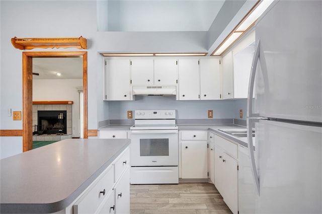 3226 Cherry Hill Cir S, Lakeland, FL 33810 - kitchen featuring a fireplace, white cabinetry, under cabinet range hood, white appliances, and light wood-style flooring