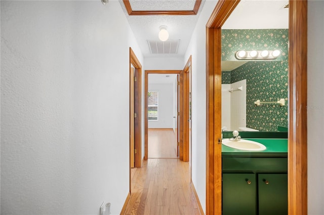 3226 Cherry Hill Cir S, Lakeland, FL 33810 - hall featuring a sink, light wood-style floors, a textured ceiling, baseboards, and visible vents