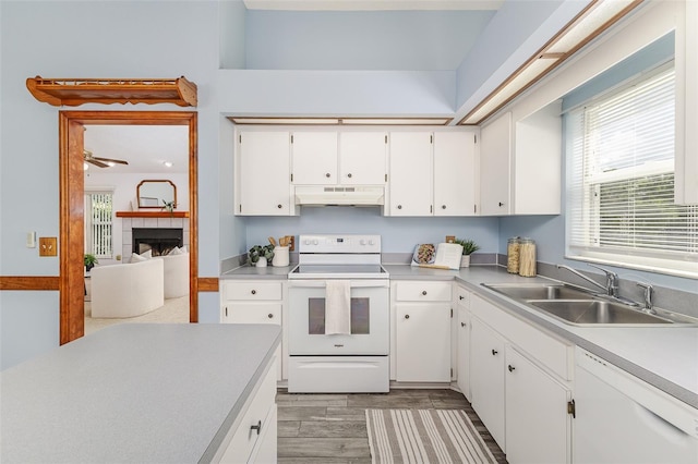 3226 Cherry Hill Cir S, Lakeland, FL 33810 - kitchen with white appliances, under cabinet range hood, light countertops, white cabinets, and a fireplace