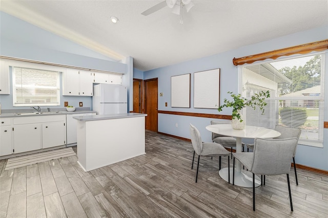 3226 Cherry Hill Cir S, Lakeland, FL 33810 - kitchen featuring freestanding refrigerator, vaulted ceiling, light wood-style flooring, white cabinets, and a center island