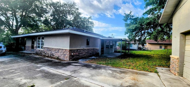 view of side of property featuring stucco siding, fence, stone siding, and driveway