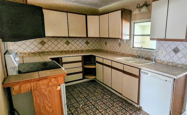 kitchen featuring white dishwasher, tasteful backsplash, range, and a sink