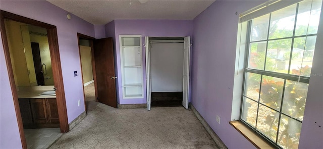 unfurnished bedroom with baseboards, carpet flooring, a sink, and a textured ceiling