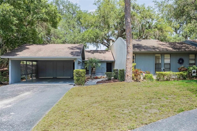 single story home featuring aphalt driveway, a front lawn, and a carport