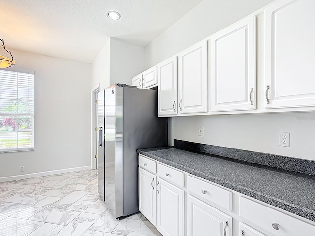 kitchen featuring marble finish floor, dark countertops, stainless steel refrigerator with ice dispenser, recessed lighting, and white cabinetry