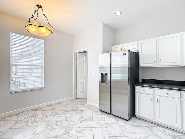 kitchen featuring marble finish floor, dark countertops, baseboards, white cabinetry, and stainless steel fridge with ice dispenser