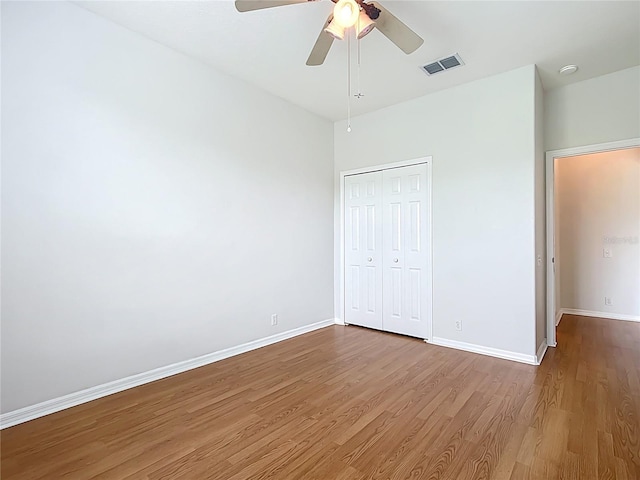 unfurnished bedroom with visible vents, baseboards, wood finished floors, and a closet