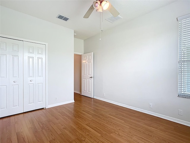 unfurnished bedroom with visible vents, baseboards, wood finished floors, and a closet