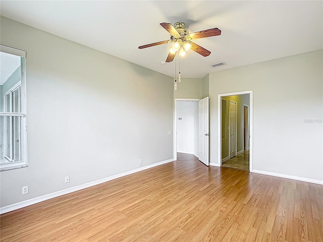 spare room featuring baseboards, a ceiling fan, light wood-type flooring, and visible vents