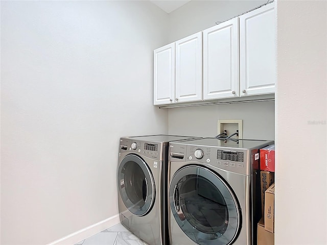 laundry room with baseboards, washing machine and dryer, cabinet space, and marble finish floor
