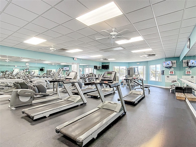 exercise room with baseboards, ceiling fan, and a paneled ceiling