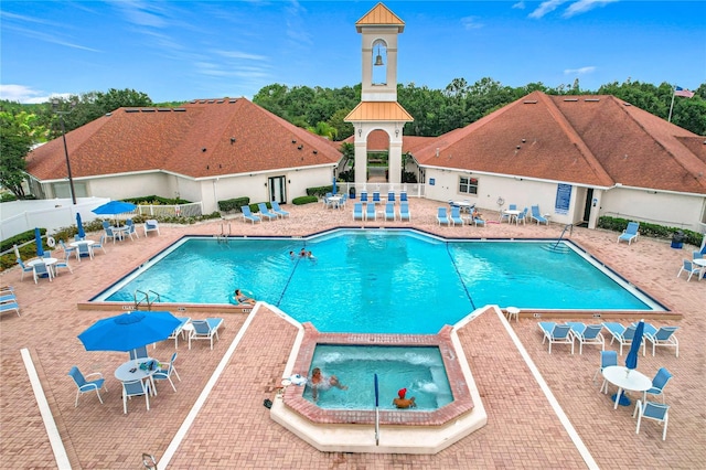 pool featuring a patio, a community hot tub, and fence