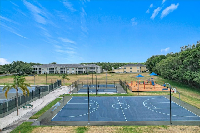 view of sport court featuring a yard, community basketball court, playground community, and fence