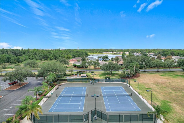 view of tennis court featuring a water view and fence