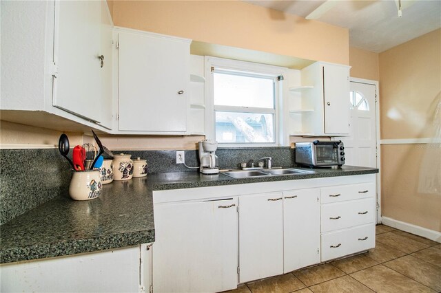 422 E Belmar St, Lakeland, FL 33803 - kitchen with white cabinets, light tile patterned flooring, open shelves, dark countertops, and a sink