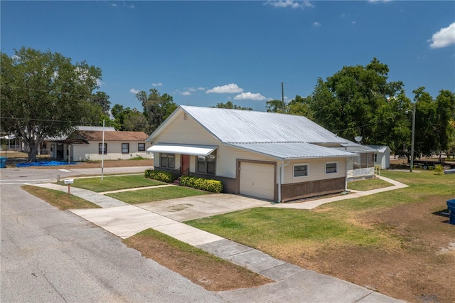 view of front facade featuring a garage, a front yard, brick siding, metal roof, and driveway