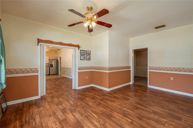 empty room with ceiling fan, wainscoting, wood finished floors, and visible vents