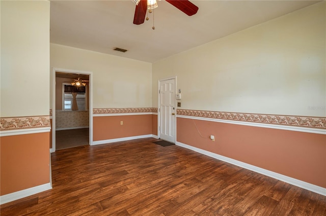 empty room featuring a ceiling fan, visible vents, wainscoting, and wood finished floors