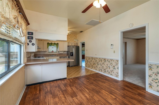 kitchen featuring wood finished floors, wallpapered walls, stainless steel fridge, light countertops, and a ceiling fan