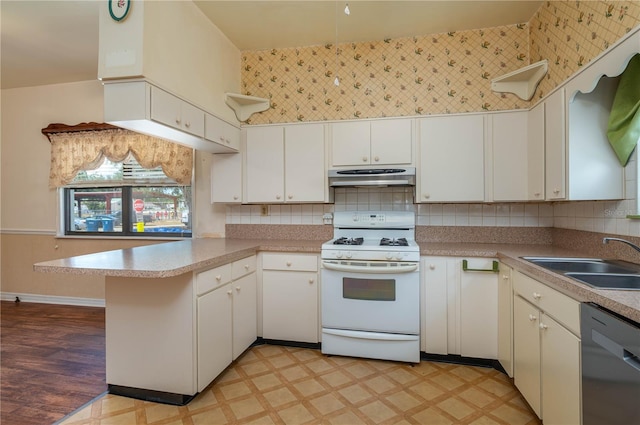 kitchen featuring a peninsula, light floors, white range with gas cooktop, a sink, and dishwasher