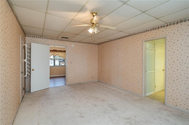 spare room featuring carpet floors, visible vents, wallpapered walls, a paneled ceiling, and a ceiling fan