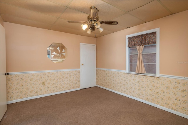 carpeted spare room featuring baseboards, a ceiling fan, a paneled ceiling, and wallpapered walls