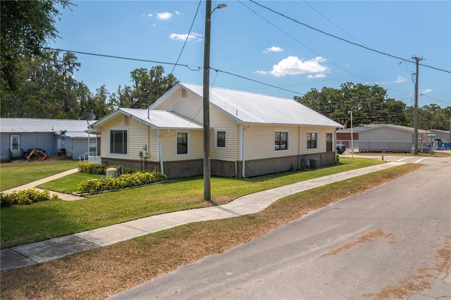 view of front of house with a front lawn, central AC, and metal roof