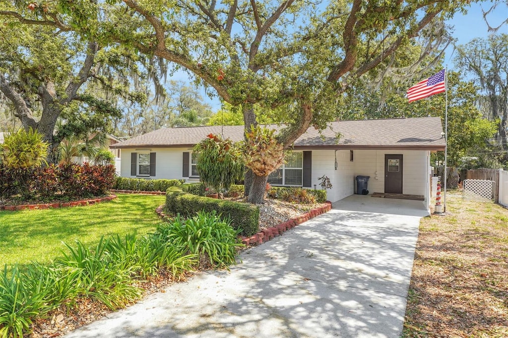 single story home with fence, concrete driveway, a front yard, and an attached carport