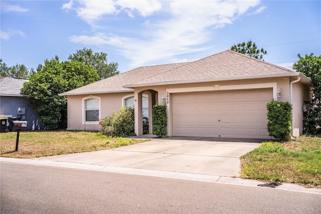 ranch-style house featuring stucco siding, a shingled roof, a garage, a front lawn, and concrete driveway