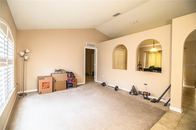 exercise room featuring arched walkways, visible vents, lofted ceiling, and baseboards