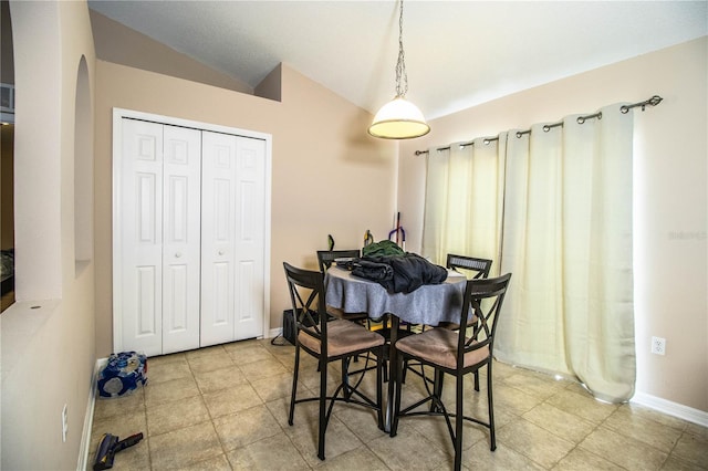 dining space with lofted ceiling, baseboards, tile patterned flooring, and arched walkways