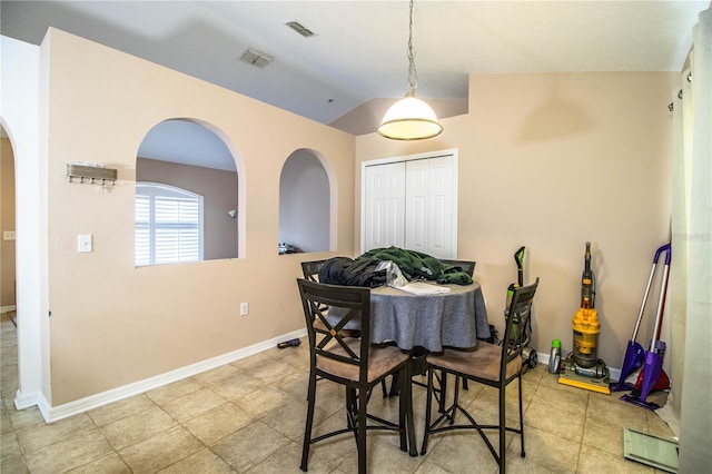 dining space with visible vents, arched walkways, vaulted ceiling, and baseboards