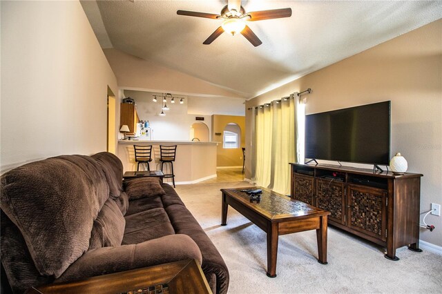 living room featuring arched walkways, ceiling fan, vaulted ceiling, and carpet floors