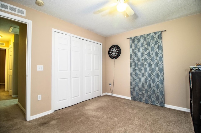 unfurnished bedroom with carpet, visible vents, a textured ceiling, and a closet