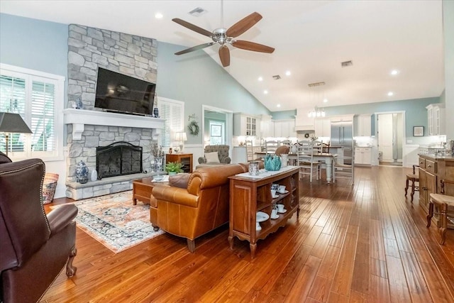 living room featuring ceiling fan, a fireplace, high vaulted ceiling, dark wood finished floors, and visible vents