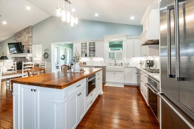 kitchen featuring butcher block countertops, a center island, white cabinetry, a sink, and stainless steel appliances