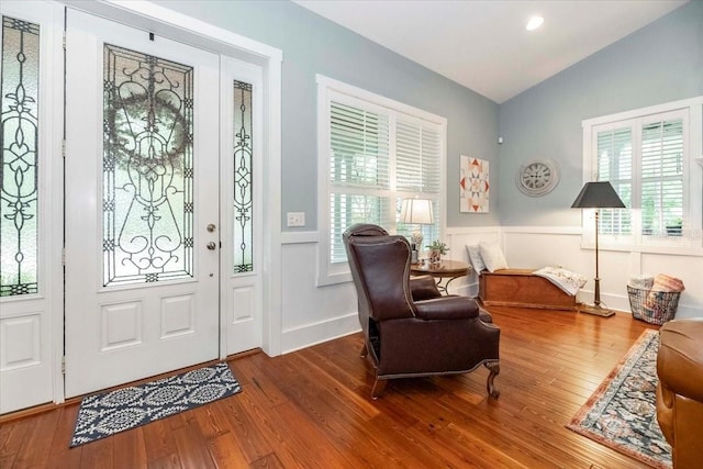 entryway with wood finished floors, wainscoting, and lofted ceiling