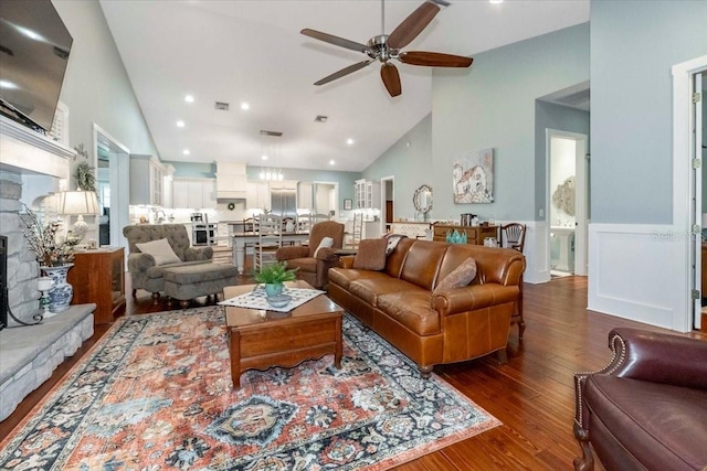 living room featuring ceiling fan, a stone fireplace, high vaulted ceiling, recessed lighting, and dark wood-type flooring