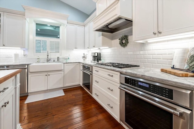 kitchen with a sink, appliances with stainless steel finishes, white cabinets, and tasteful backsplash