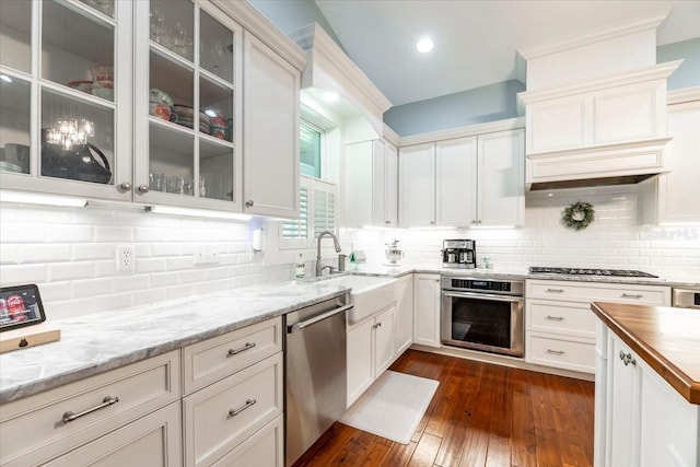 kitchen with decorative backsplash, appliances with stainless steel finishes, white cabinets, and glass insert cabinets
