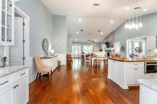 kitchen featuring visible vents, dark wood-style flooring, glass insert cabinets, white cabinetry, and a ceiling fan