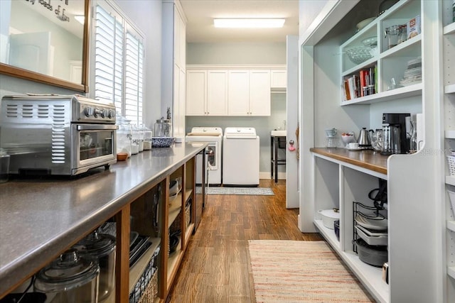 clothes washing area with a toaster, washing machine and dryer, cabinet space, and dark wood-type flooring