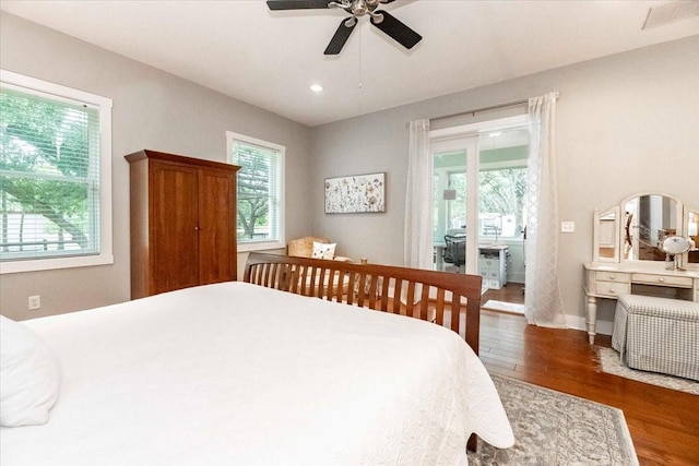 bedroom with baseboards, wood finished floors, and multiple windows