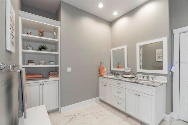 bathroom featuring baseboards, a sink, marble finish floor, and double vanity