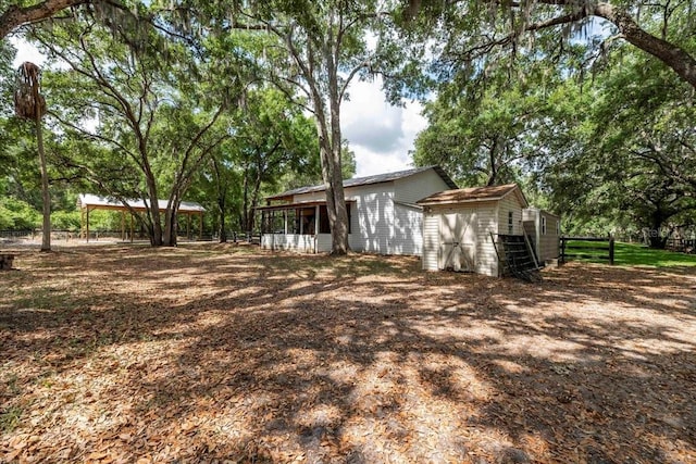 back of property with fence, an outbuilding, a shed, and a sunroom