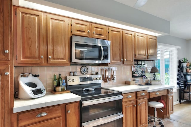 4116 4th Ave NE, Bradenton, FL 34208 - kitchen featuring tile counters, appliances with stainless steel finishes, and tasteful backsplash